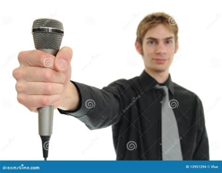 a man holding a microphone up to his mouth while standing in front of a