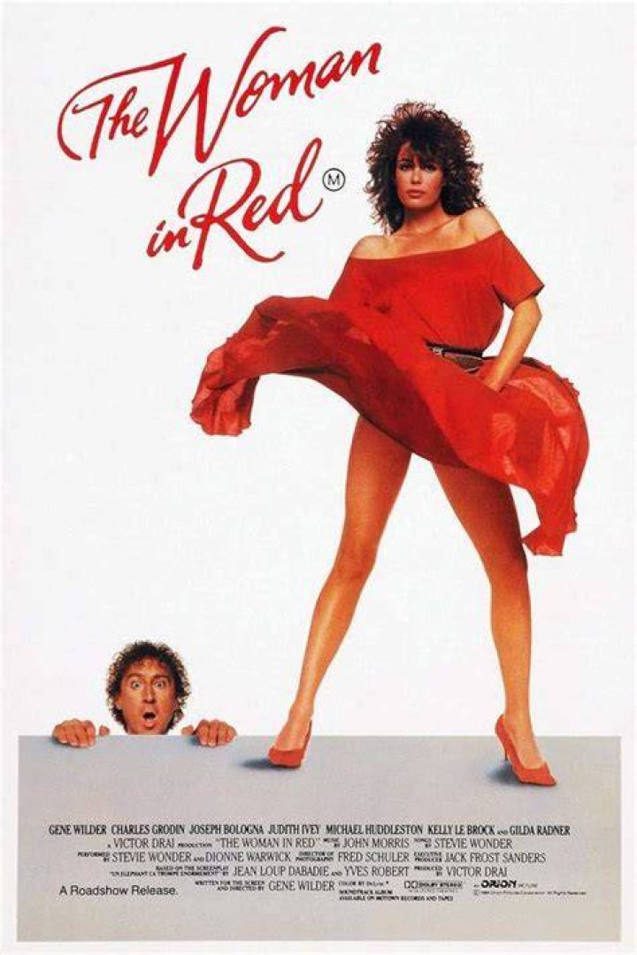 a woman in a red dress posing for the camera with her hand on her face